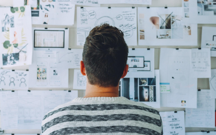 the back of someone standing looking at a wall of papers
